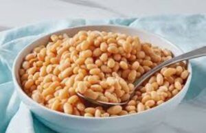 Nutritionists’ Pronouncement: Beans Contain More Carbohydrates Than Protein White bowl filled with cooked chickpeas and a metal spoon resting in them on a light blue cloth