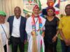 APC-South Africa Inaugurates Mpumalanga Executives, Strengthens Mobilisation For 2027 Election Five people pose at a political event; central man in white robes with a colorful scarf, others in smart attire, APC banner in the back.