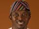 Oyo Warns Residents Of Flash Floods, Calls For Strict Adherence To Safety Measures Portrait of a smiling man wearing a colorful striped headwrap and white traditional attire against a warm brown background.
