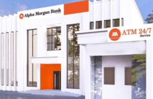 How We Posted ₦1.9 Billion PBT In First 10 Months Of Operations – Alpha Morgan Bank Exterior of an Alpha Morgan Bank branch with white modern facade, orange accents, and an ATM-24/7 service sign.