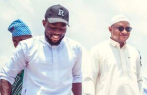 Barr Akeem Agbaje Celebrates Asiwaju Adekola Mudashir On Birthday Three men walking outdoors, smiling; center man in a white kurta, cap with 'R', right man in sunglasses.