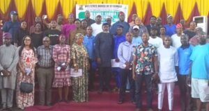 Oyo Assembly Assures Cleaner, Healthier Environment As Public Hearing On Single-Use Plastics Prohibition Bill Holds Group of men and women posing on a stage at a formal assembly event, with a banner in the background and yellow/red drapery behind them.