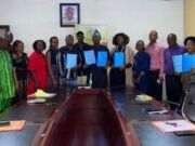 Boost For Students’ Training/Innovation: FCA Ibadan Signs Strategic Agribusiness Partnerships Group of professionals around a conference table holding blue folders, suggesting a signing or agreement ceremony.