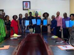 Boost For Students’ Training/Innovation: FCA Ibadan Signs Strategic Agribusiness Partnerships Group of professionals around a conference table holding blue folders, suggesting a signing or agreement ceremony.