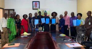 Boost For Students’ Training/Innovation: FCA Ibadan Signs Strategic Agribusiness Partnerships Group of professionals around a conference table holding blue folders, suggesting a signing or agreement ceremony.