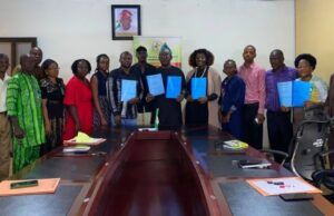 Boost For Students’ Training/Innovation: FCA Ibadan Signs Strategic Agribusiness Partnerships Group of professionals around a conference table holding blue folders, suggesting a signing or agreement ceremony.