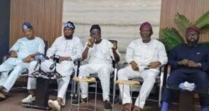 Guber 2027: Five Aspirants Call For Oyo APC Chairman’s Resignation Five men seated in a row at a conference, one speaking into a microphone while others listen, in traditional outfits with neutral backdrop.