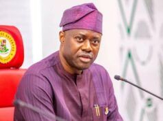 Pity Fayose, Pray For Him, Makinde Tells Nigerians Man in a purple traditional outfit and cap speaks into a microphone at a formal meeting, seated behind a desk with pens in his chest pocket.