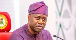 Pity Fayose, Pray For Him, Makinde Tells Nigerians Man in a purple traditional outfit and cap speaks into a microphone at a formal meeting, seated behind a desk with pens in his chest pocket.