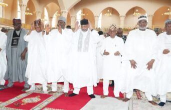 2026 Democracy Day: Be Hopeful For Peace, Unity; Clerics Urge Nigerians Group of men in white traditional robes and caps standing on a red prayer rug inside a mosque, some with hands raised in prayer.