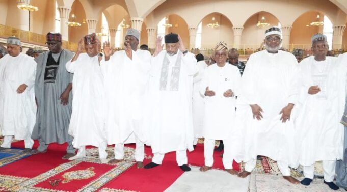 2026 Democracy Day: Be Hopeful For Peace, Unity; Clerics Urge Nigerians Group of men in white traditional robes and caps standing on a red prayer rug inside a mosque, some with hands raised in prayer.