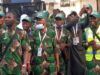 2026 Hajj: Oyo’s First, Second Batch Pilgrims Set For Return To Nigeria Group of men in matching green camouflage outfits and green caps posing together, some with lanyards and a high-visibility vest in the crowd.