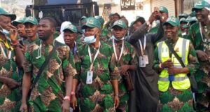 2026 Hajj: Oyo’s First, Second Batch Pilgrims Set For Return To Nigeria Group of men in matching green camouflage outfits and green caps posing together, some with lanyards and a high-visibility vest in the crowd.