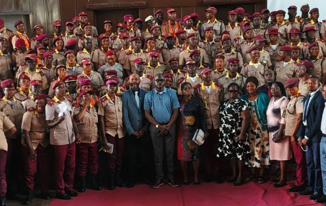OYROMA Large group of uniformed officers with red berets posing for a formal group photo, civilians in front on a red carpet.