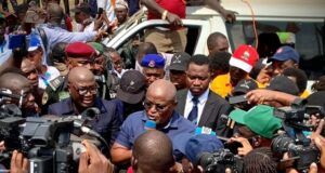 Oyo School Abduction: Obasa Reaffirms Push For State Police Amid NUT Protest Politician or speaker addressing a crowded media scrum with multiple cameras and microphones around him near a white vehicle.
