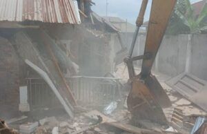 Makinde’s Govt Demolishes Building Used By Kidnappers Of Adelabu’s Sister, Nephews Excavator bucket amid collapsed brick walls and scattered debris at a demolition site with dust in the air.