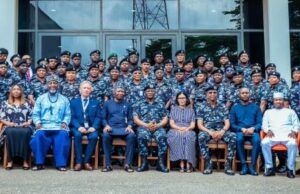 IGP Charges Officers To Drive Police Reform, Embrace Innovation Large group photo of uniformed military personnel and civilian officials seated in front of a glass-front building outdoors.