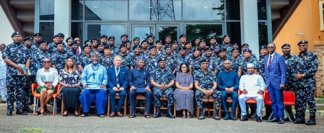 Police with IGP Large group photo of uniformed military personnel and civilian officials seated in front of a glass-front building outdoors.