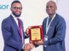 Shell Identifies Strategic Pathways To Advance Gas Utilisation At Abuja Business Forum Two men in business attire shake hands as one presents a wooden plaque award