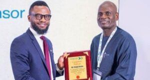 Shell Identifies Strategic Pathways To Advance Gas Utilisation At Abuja Business Forum Two men in business attire shake hands as one presents a wooden plaque award