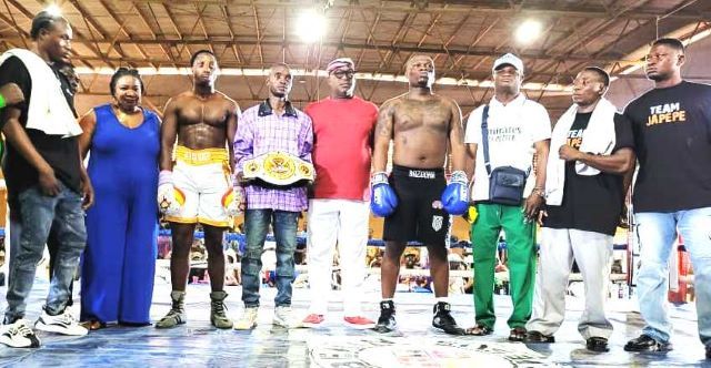 Stop Killing Boxing Group of boxers and coaches posing in a boxing ring; one fighter wears a championship belt across the waist.