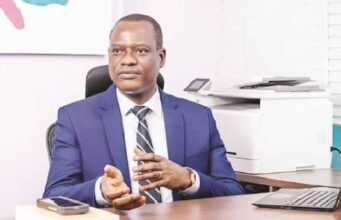 Federal Gov’t Cuts Ministers’ Imprest To N700,000, Tightens Spending Rules Professional man in a blue suit seated at a desk in an office, gesturing with his hands as he speaks.